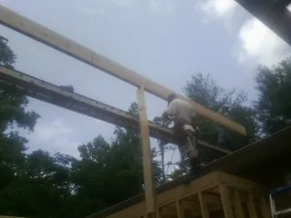 Carpenter setting a ridge beam over a new addition frame — Ice Dam Removal by Roofing Brothers in Alliance