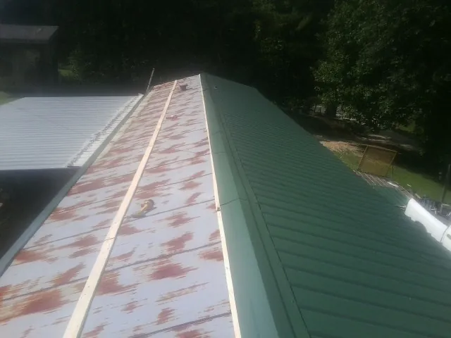 Old rusted panels beside newly installed green metal roofing — Wind Damage Roof Repair by Roofing Brothers in Alliance