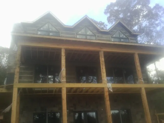 Dormers and porch framing on a large log home under construction — Roof Coating work by our crew in Alliance
