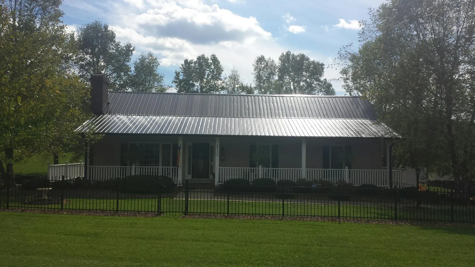 Gray metal roof on a brick ranch with a full width front porch — Gutter Guard Installation work by our crew in Alliance