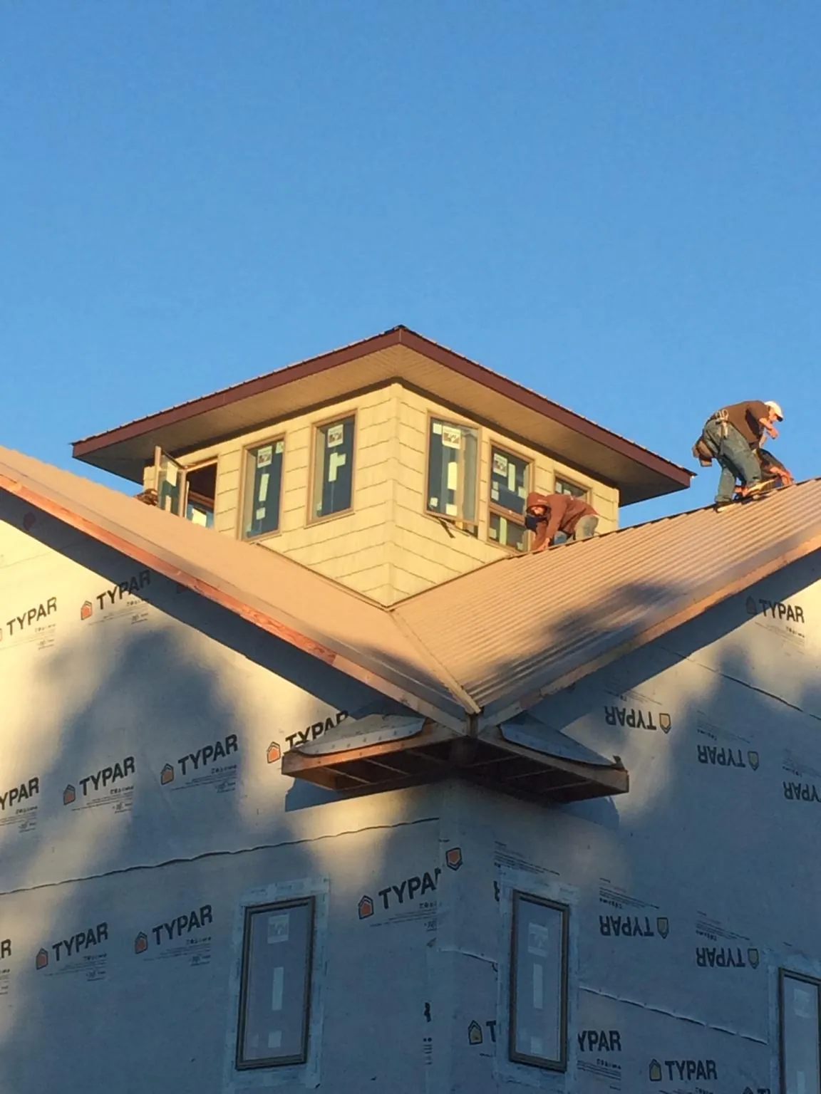 Roofers working around a rooftop cupola on a new metal roof at sunset — Roof Waterproofing in Alliance by Roofing Brothers